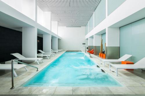 a large swimming pool in a building with white chairs at Hotel Spa Calagrande Cabo de Gata in Las Negras