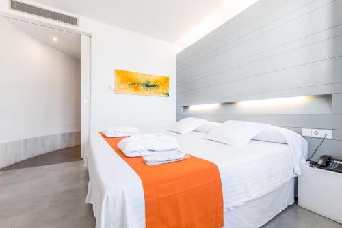 a white bedroom with a bed with an orange blanket at Hotel Spa Calagrande Cabo de Gata in Las Negras