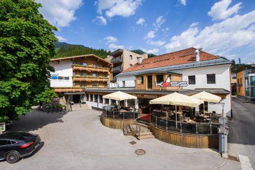 a building with tables and umbrellas on a street at KOSIS Sports Lifestyle Hotel in Fügen