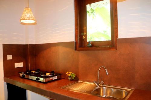 a kitchen with a sink and a stove and a window at Lilly House in Unawatuna