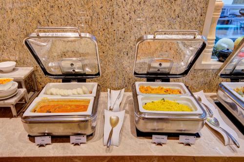 a buffet with several trays of food on a counter at Niranta Transit Hotel Mumbai Airport - At Arrivals in Mumbai