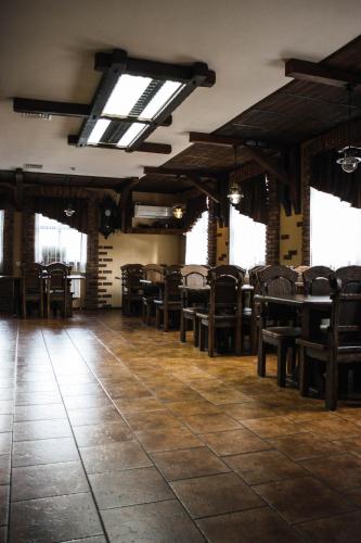 a dining room with chairs and tables and windows at Stara Vezha Hotel in Boryspilʼ