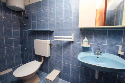 a blue tiled bathroom with a toilet and a sink at Robinson Tabinja in Sućuraj