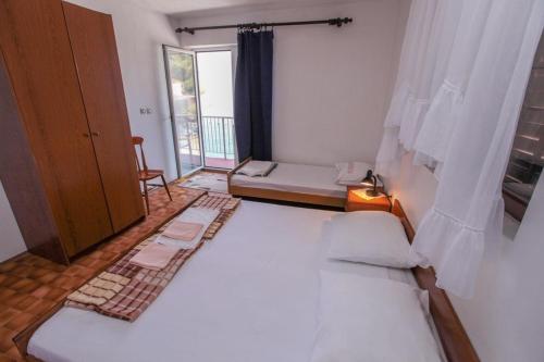 a bedroom with a large white bed and a window at Robinson Tabinja in Sućuraj
