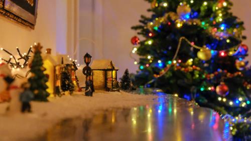 a christmas tree and a toy house in front of a christmas tree at Private Castle with Park - Château Guillermo in La Moncelle