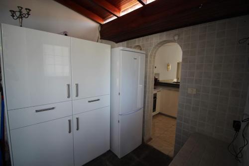 a kitchen with white cabinets and an arched doorway at Sunny House, Chayofa in Chayofa
