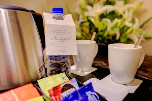 a bottle of water and two cups on a table at Niranta Transit Hotel Mumbai Airport - At Arrivals in Mumbai