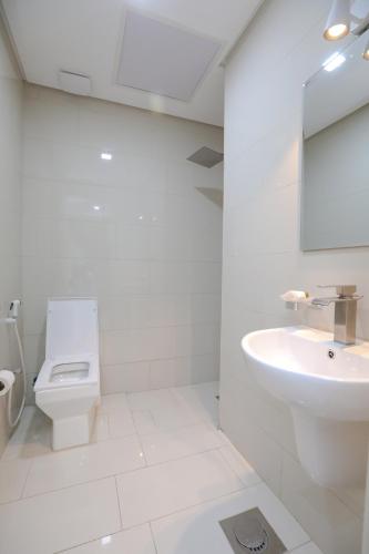 a white bathroom with a toilet and a sink at ماجيك سويت بوليفارد Magic Suite Boulevard in Kuwait