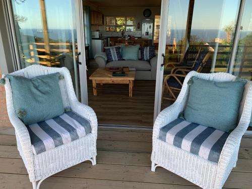 two wicker chairs sitting on a porch at Trinity Farm Ocean view Cottage in Plettenberg Bay