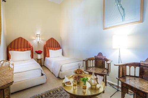 a hotel room with two beds and a table at Riad Azoulay in Marrakech