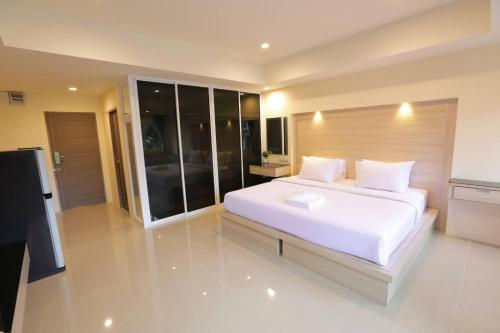 a bedroom with a large white bed and a television at Lampang Residence in Lampang