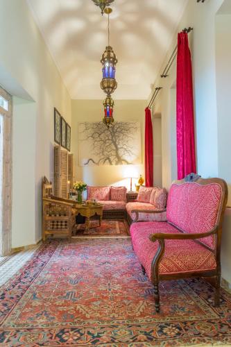 a living room with pink furniture and a chandelier at Riad Azoulay in Marrakech