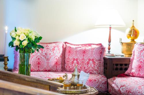 a living room with a couch and a vase of flowers at Riad Azoulay in Marrakech