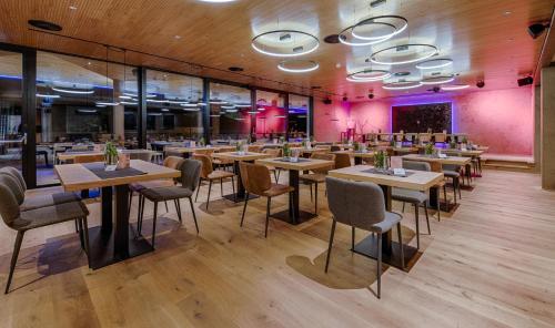 a restaurant with tables and chairs and pink walls at KOSIS Sports Lifestyle Hotel in Fügen