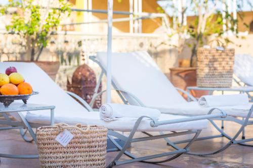 a table with two chairs and a table with fruit on it at Riad Azoulay in Marrakech