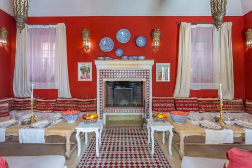 a red dining room with tables and a fireplace at Riad Azoulay in Marrakech