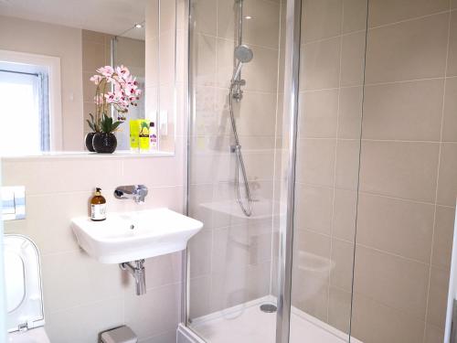 La salle de bains est pourvue d'une douche et d'un lavabo. dans l'établissement Reading New Luxury House Wz Garden&Parking by L&S, à Reading