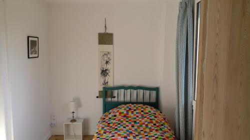 a room with a crib with a colorful blanket on it at Ancien presbytère in Le Torpt