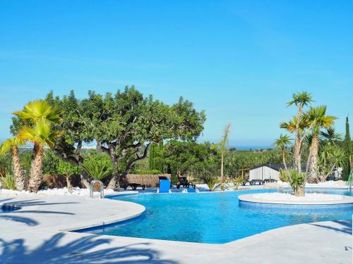 a resort swimming pool with palm trees and chairs at Camping L'Orangeraie in Cálig