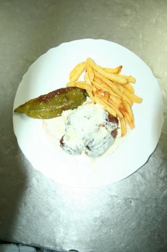 a plate of food with a pickle and french fries at Bungalows Camping Parque Nacional de Monfragüe in Malpartida de Plasencia