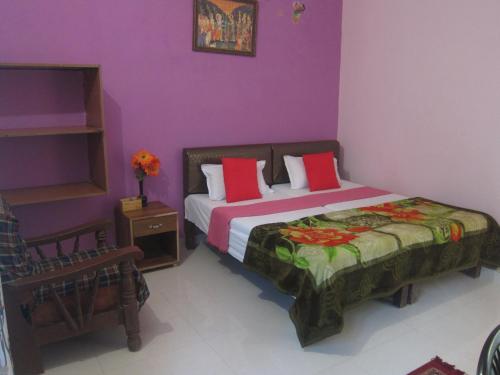 1 dormitorio con 1 cama con almohadas rojas y paredes moradas en Kedar Guest House -Feel At Home, en Varanasi
