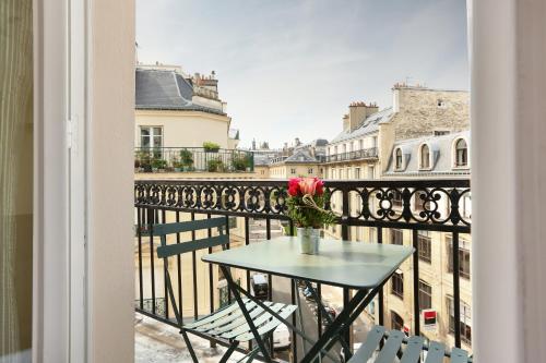 a table with a vase of flowers on a balcony at Hotel du College de France in Paris
