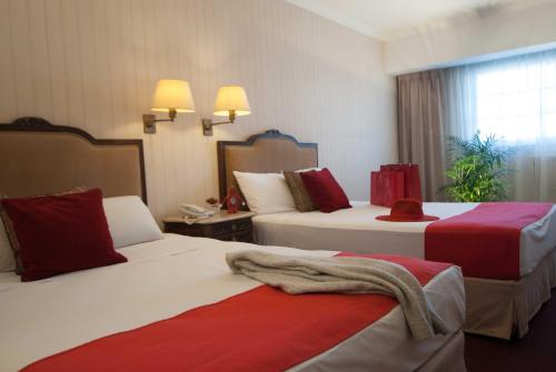 a hotel room with two beds with red and white at Ramada by Wyndham Buenos Aires Centro in Buenos Aires