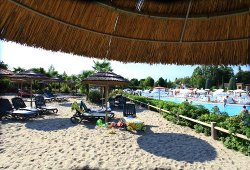 una spiaggia con sedie e ombrelloni e una piscina di Mobilhome Victoria Bella Italia a Peschiera del Garda