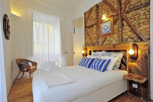 a bedroom with a bed with a stone wall at Localtraveling ALFAMA River View - Family Apartments in Lisbon
