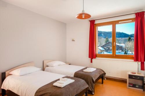 two beds in a room with a window at Village vacances Chalet de la Haute-Joux in Cerniébaud