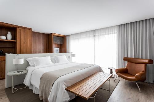 um quarto com uma cama grande e uma cadeira em Nomaa Hotel em Curitiba