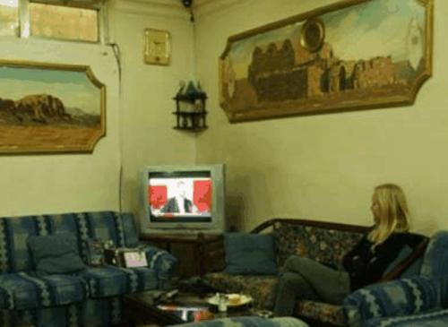 a woman sitting on a couch in a living room at Farah Hotel in Amman