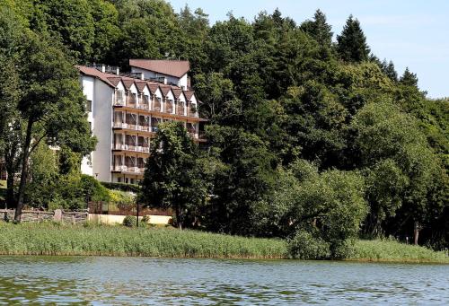 a large building sitting on the side of a river at Hotel Mazuria Country & SPA in Mrągowo
