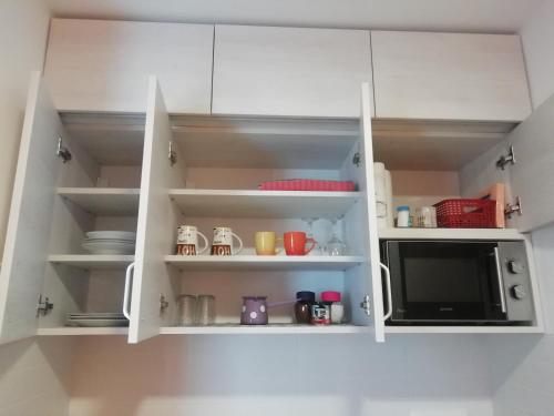 a kitchen with white cabinets and a microwave at Apartman Centar 2 in Užice