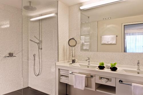 a bathroom with a sink and a shower and a mirror at Estrel Berlin in Berlin