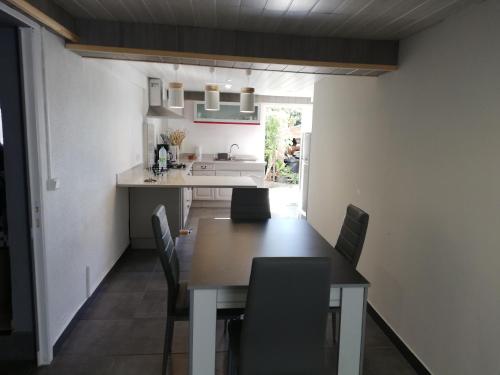a dining room with a table and chairs and a kitchen at Appartement spacieux in Sainte-Marie