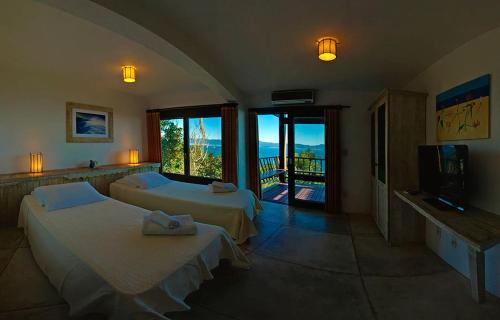 a hotel room with two beds and a balcony at Resort Refúgio do Estaleiro in Porto Belo