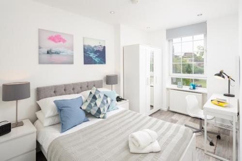 a white bedroom with a bed and a desk at Skyline Serviced Apartments - Beckett in London