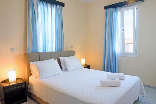 a bedroom with a bed with blue curtains and a window at Sea Breeze Apartments Chios in Monolia