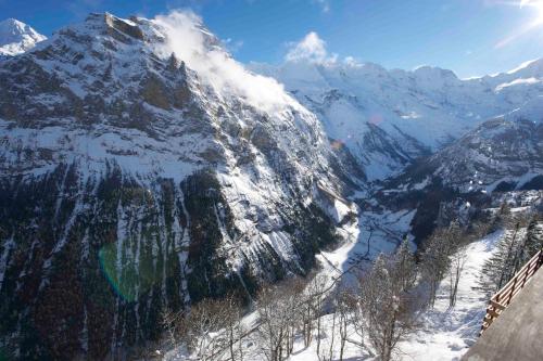 a snow covered mountain with a lake in front of it at Hotel Alpina in Mürren