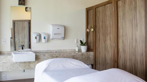 um quarto com uma cama, um lavatório e um espelho em Jatiuca Hotel & Resort em Maceió