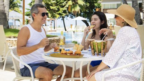 a group of people sitting around a table eating food at Jatiuca Hotel & Resort in Maceió