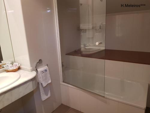 y baño con ducha acristalada y lavamanos. en Hotel Meleiros, en Castro de Sanabria