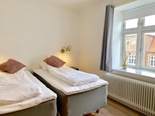 two twin beds in a room with a window at Hotel Schaumburg in Holstebro
