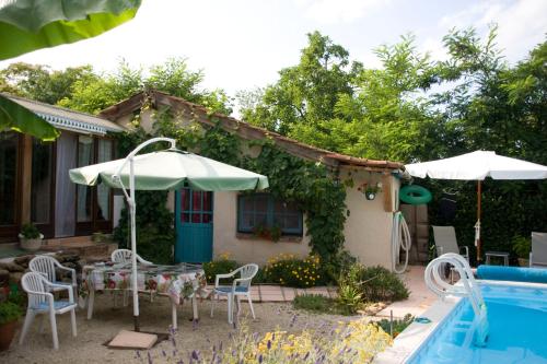 a patio with a table and chairs and a pool at Chambre d'Hôtes Oeuil de Bouc in Madiran