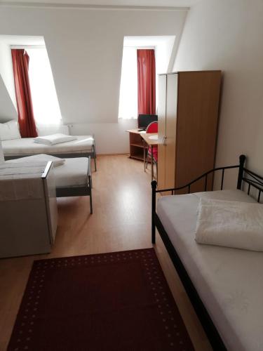 Habitación pequeña con 2 camas y escritorio. en Pension Feldschlössl, en Ingolstadt