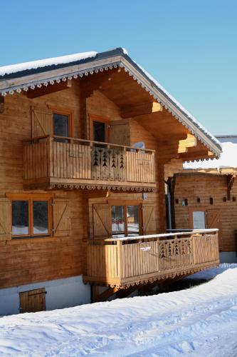 a wooden house with a deck in the snow at Résidence Néméa Les Chalets du Bois de Champelle in Morillon