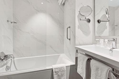 a white bathroom with a tub and a sink at Exe Paris Centre in Paris