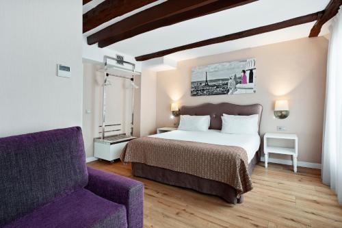 1 dormitorio con cama y sofá púrpura en Exe Paris centre, en París