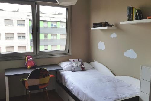 a bedroom with a bed and a desk and a window at Lauredal - Ático con amplia terraza, 2 hab, 2 baños, pádel, parque infantil in Gijón